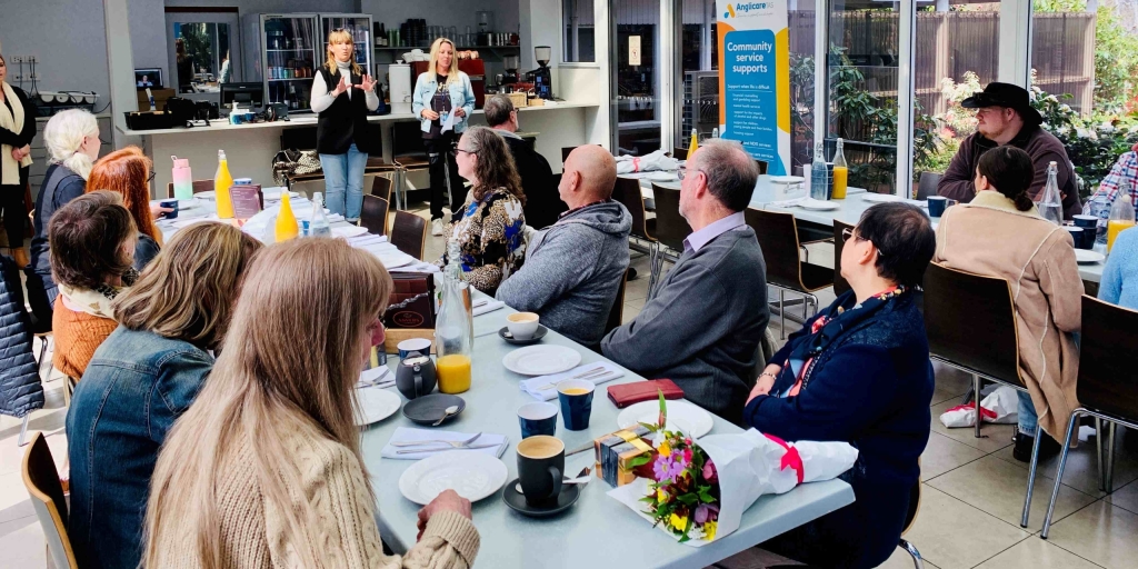 A group of people sit at a conference table listening to two speakers who are explaining the support that is available to Tasmanians who care for someone who has an addiction.